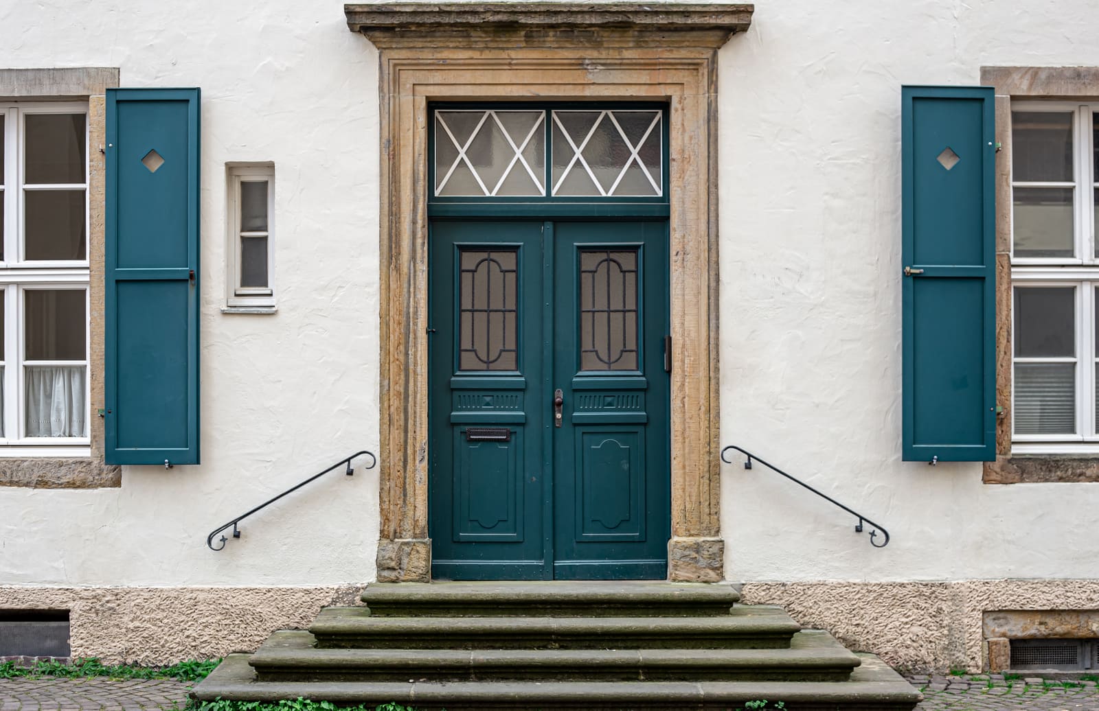 Symmetrical green double entry doors with a transom window